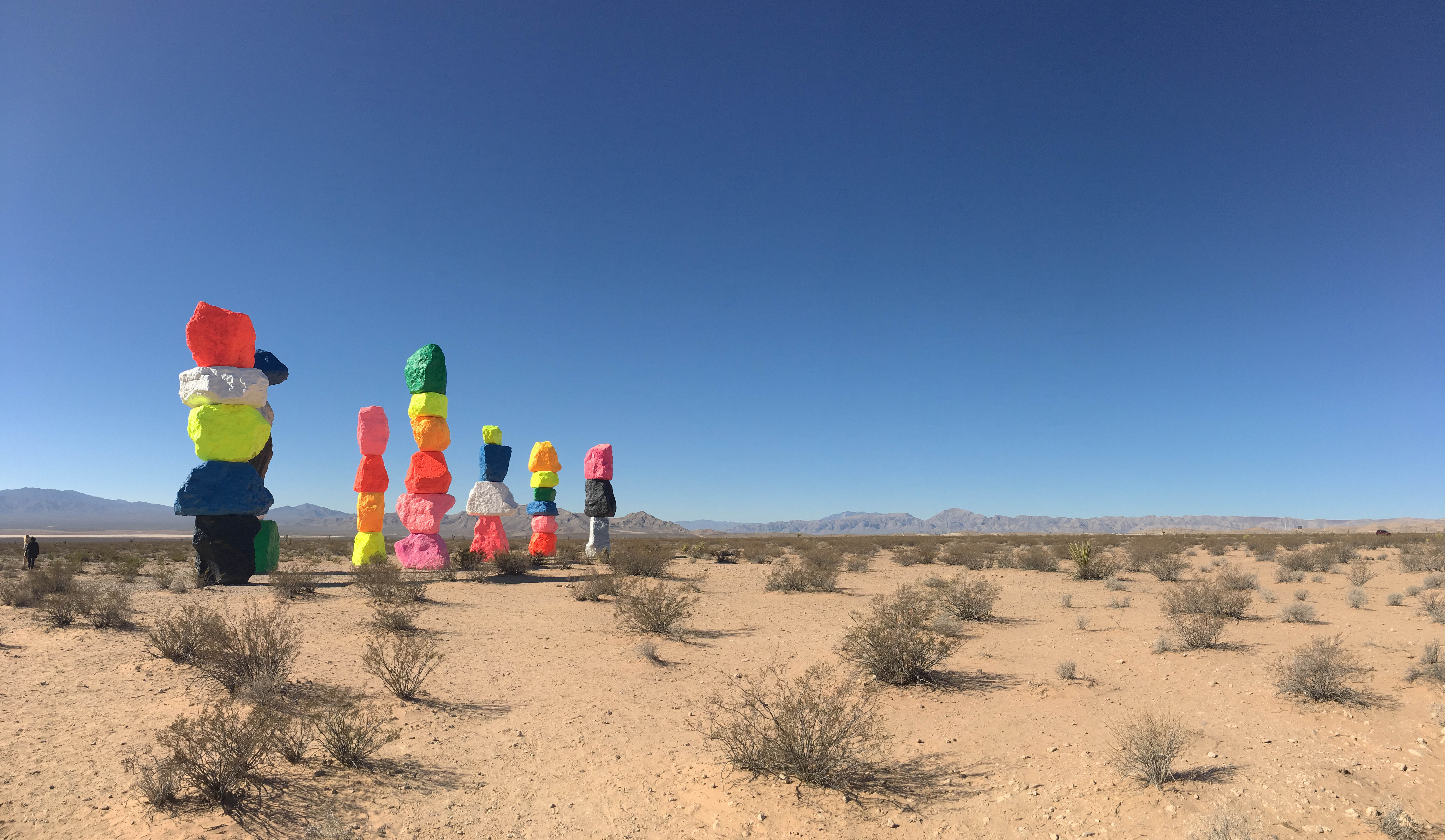 stacked neon boulders sculpture in the desert