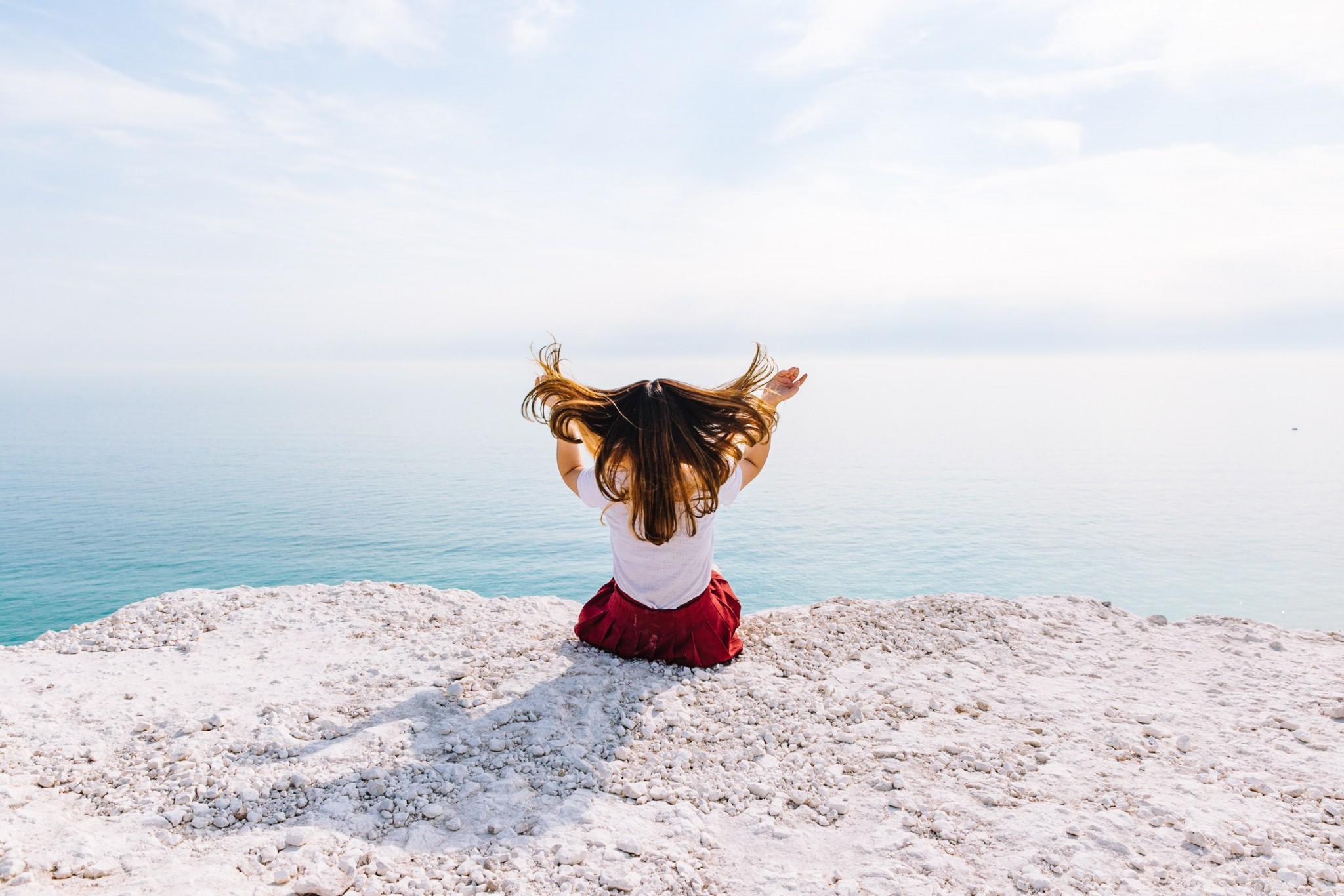 Girl sitting out looking over the sea | Why the secret to happiness might be joy