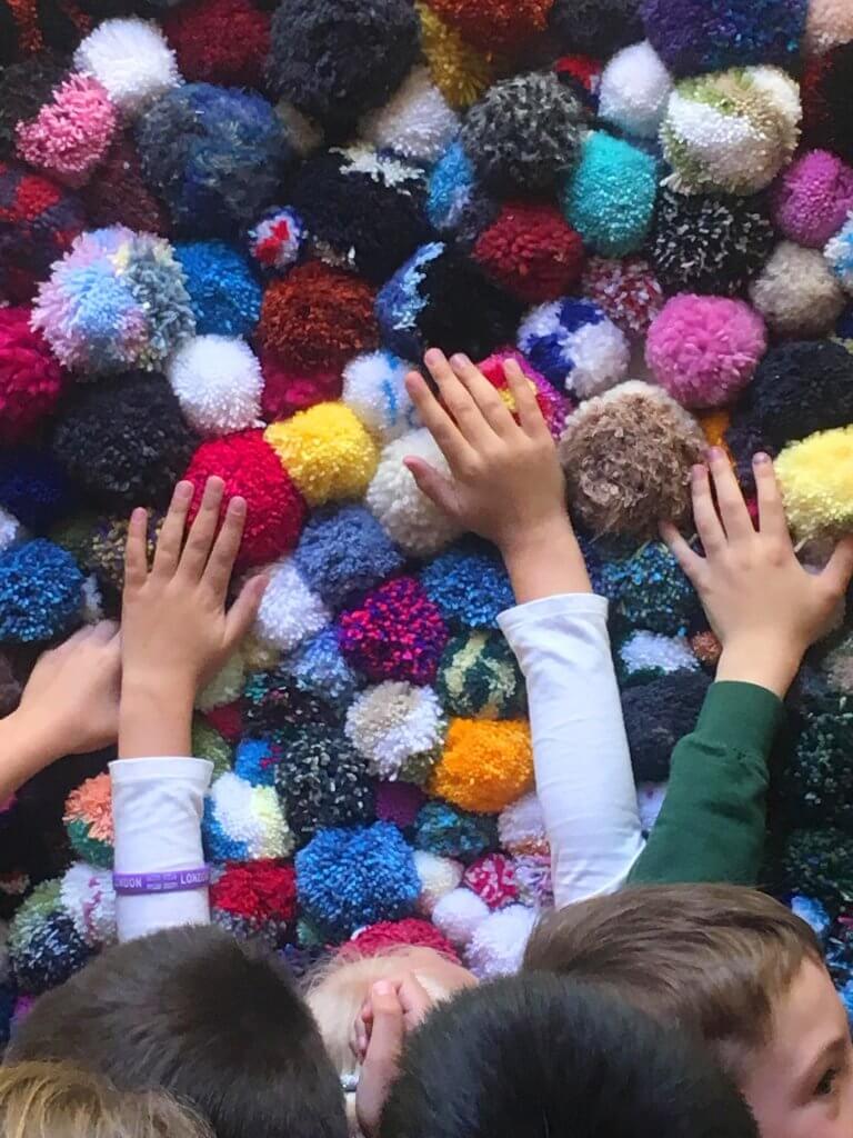 children feeling interactive pompom wall