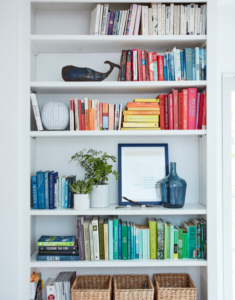 Image of color coded bookshelves in Ingrid Fetell Lee's home, showing a blue framed piece of art