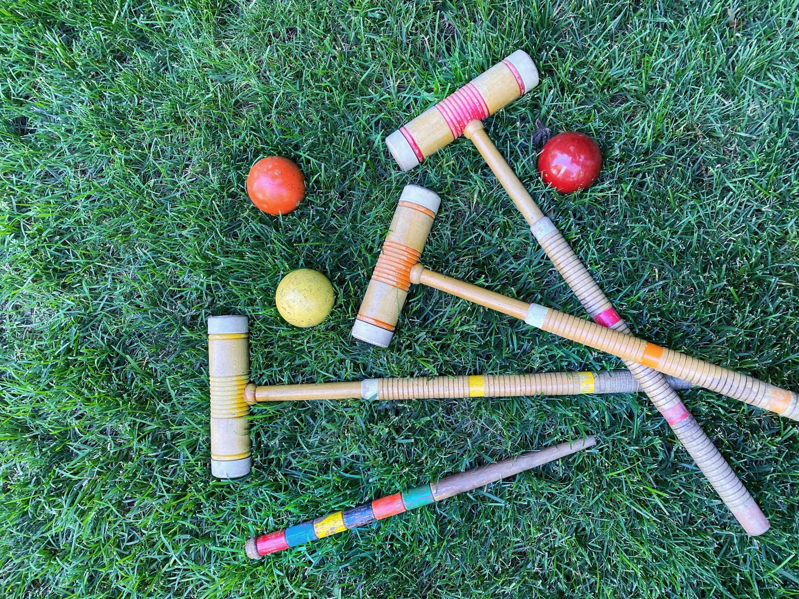 A vintage set of croquet mallets on a lawn.