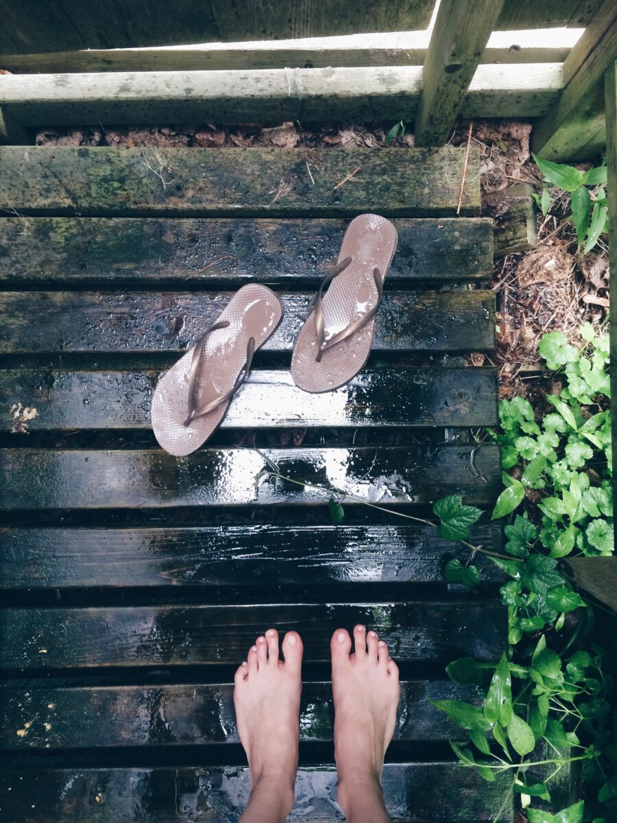 Two flip flops on the floor of an outdoor shower.