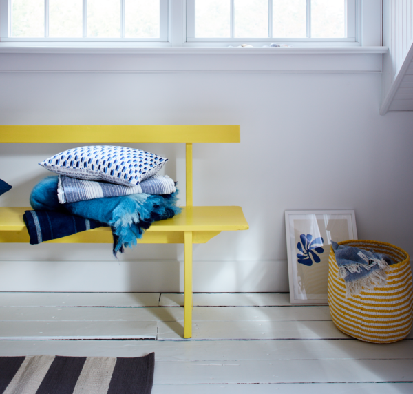 A yellow bench with blue blankets and throw pillow in the home of Ingrid Fetell Lee, photographed by Johnny Miller.