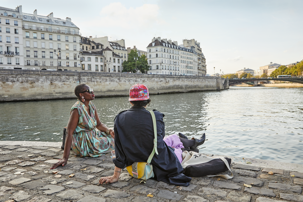Ajiri Aki and a friend sitting in front of the Seine in Paris