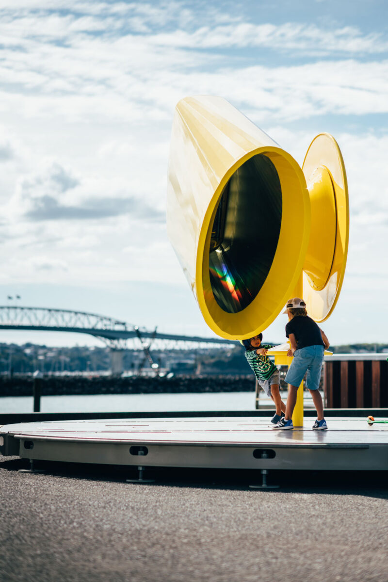 A view of the Rainbow Machine installation that shows a prismatic reflection in the inside of the large yellow tube. 
