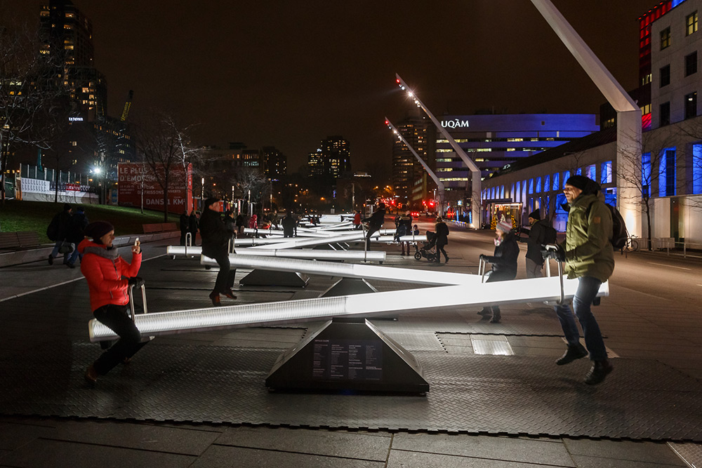 People ride glowing seesaws at night as part of the Impulse exhibit in Montreal