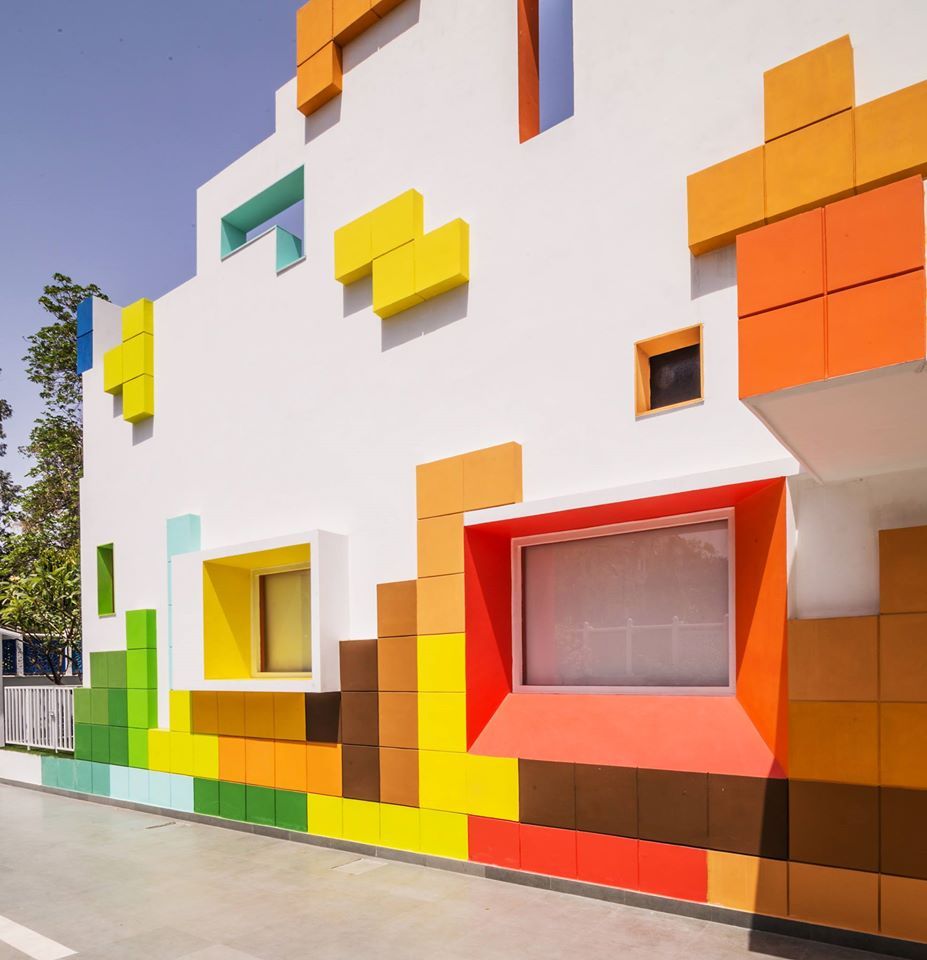 A school building facade with Tetris-like shapes in yellow, orange, and green. 