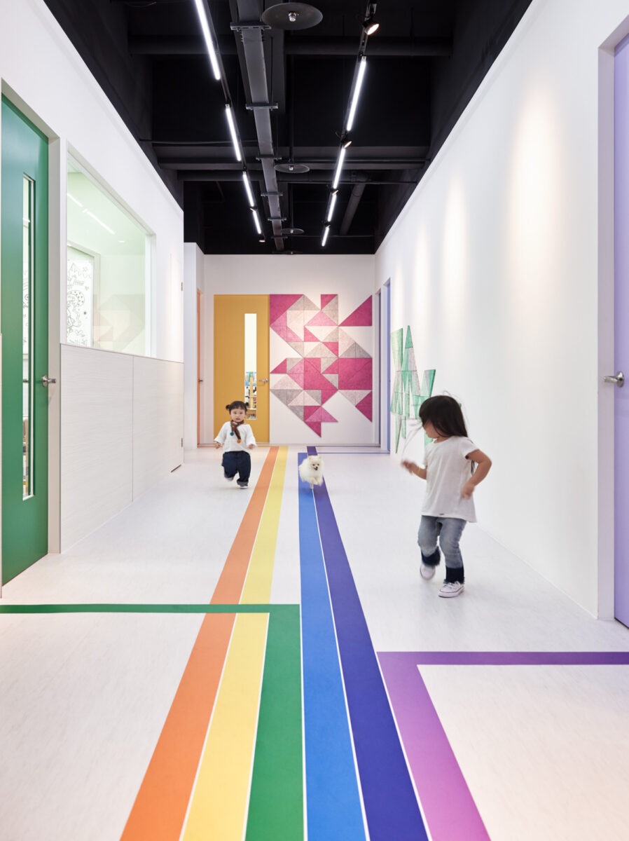 A preschool hallway with a rainbow stripe where purple and green turn at right angles to point toward purple and green classrooms