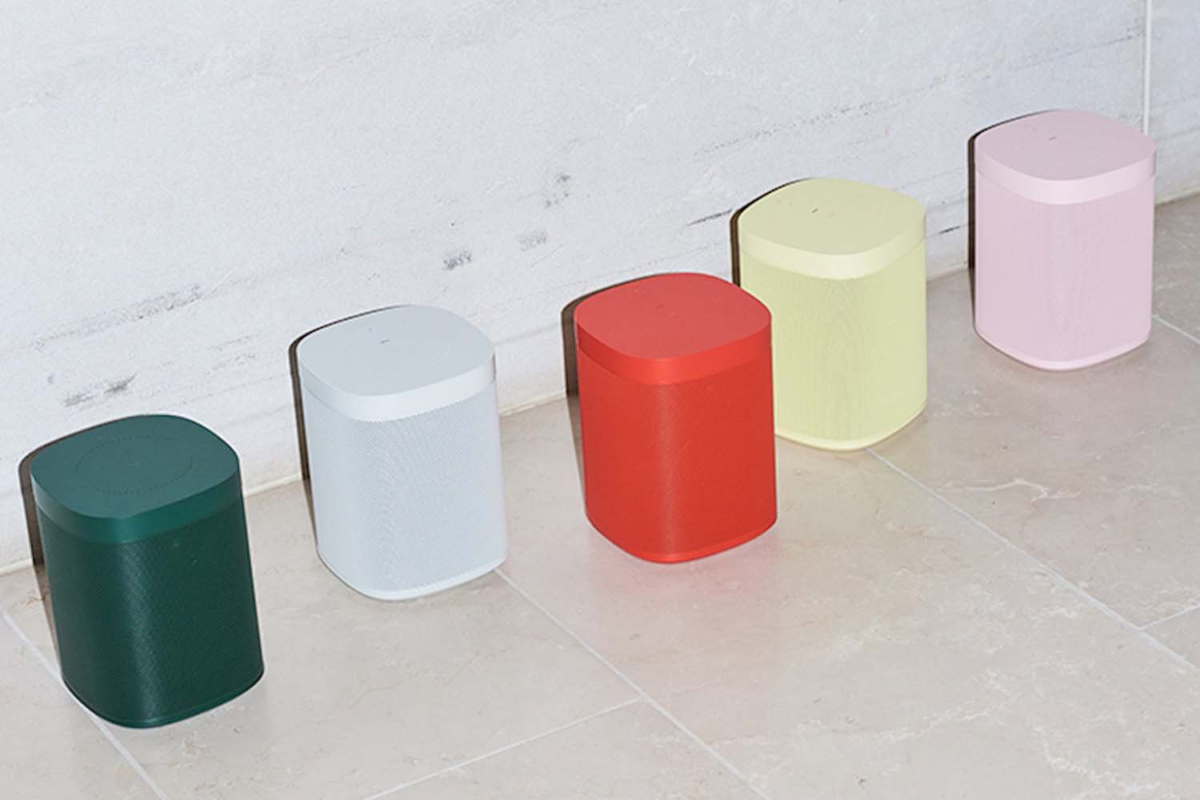 A lineup of 5 Sonos one speakers designed by Hay in colors dark green, white, red, light yellow, and light pink. 