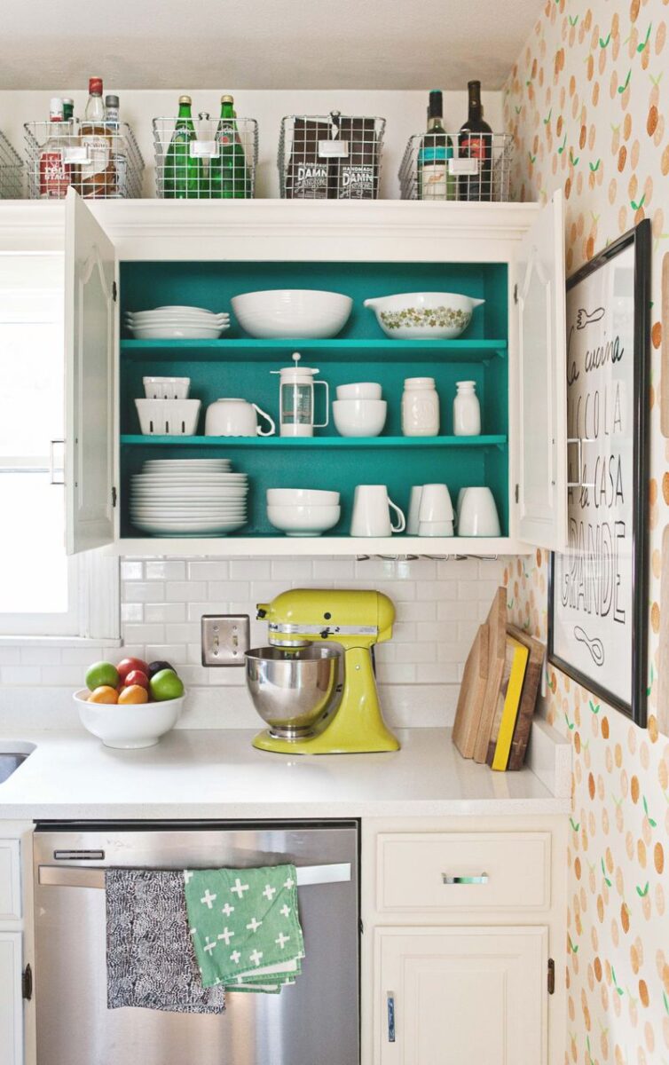 White kitchen cupboards with teal paint on back of cupboard and on shelves