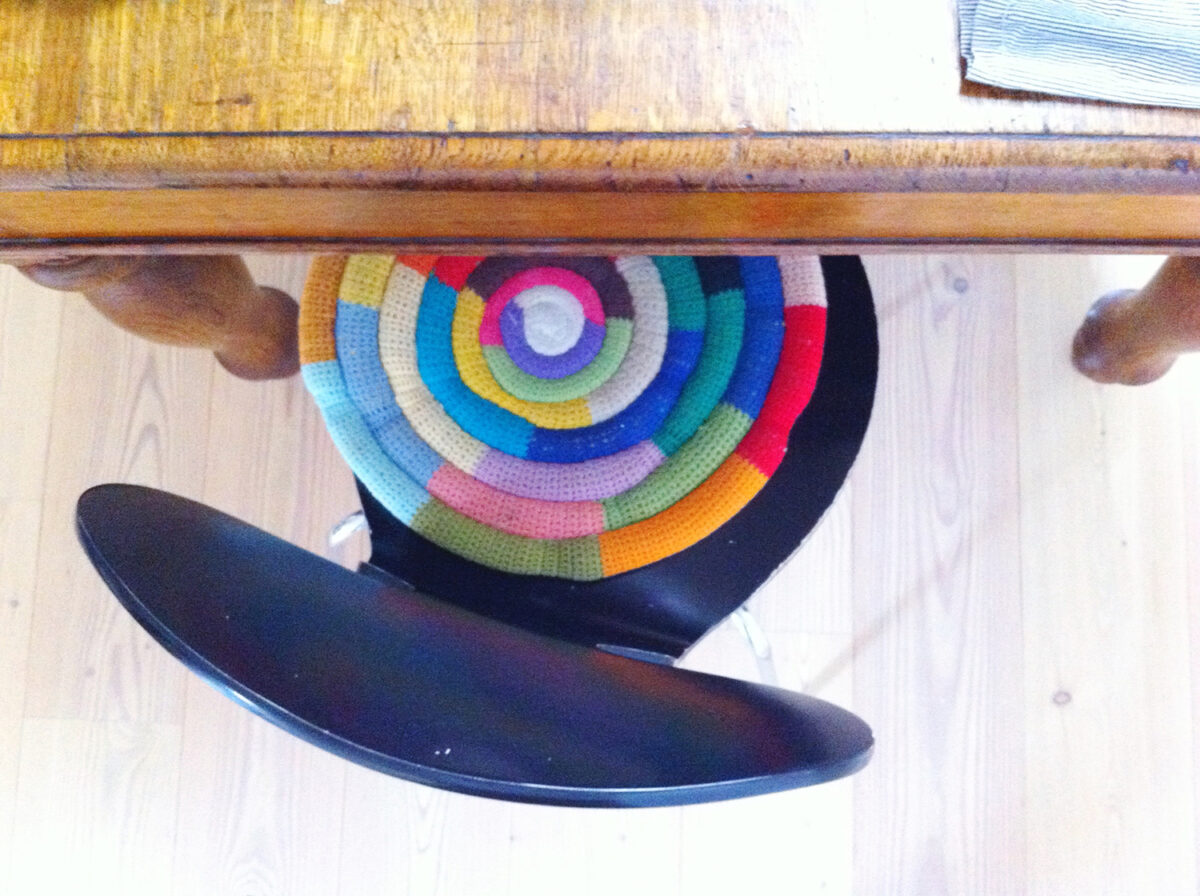 A colorful spiral cushion on a black desk chair. 