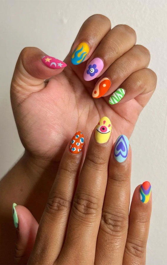 Multicolored different designs on nails include an eye, flower, moon, stars, and heart